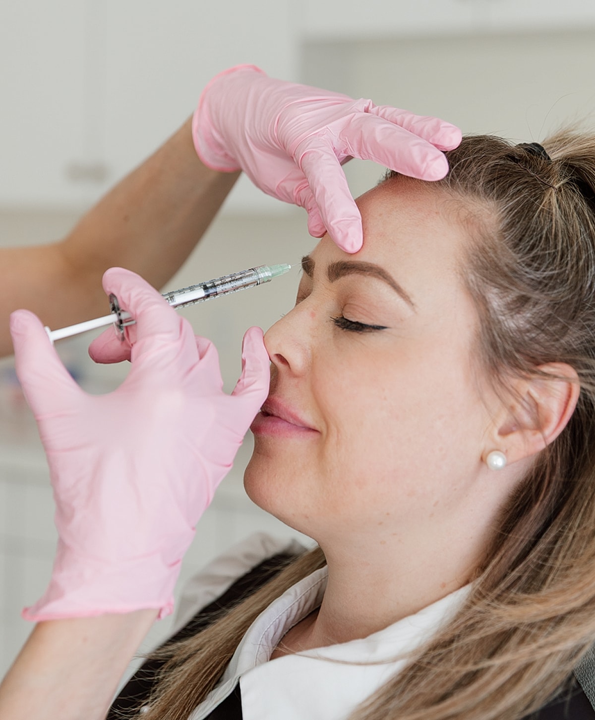 Woman receiving cosmetic injection in clinic setting.