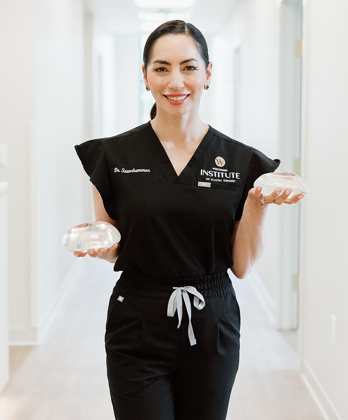 Doctor holding silicone breast implants in clinic.