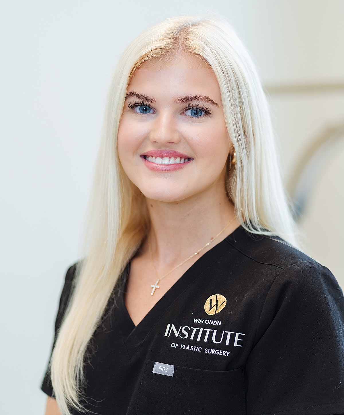 Female medical professional in black scrubs smiling.