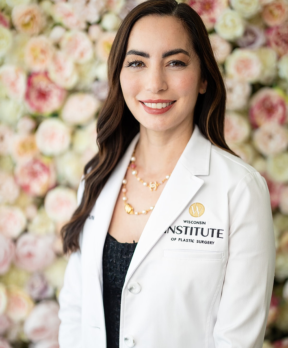 Female doctor posing in floral backdrop.