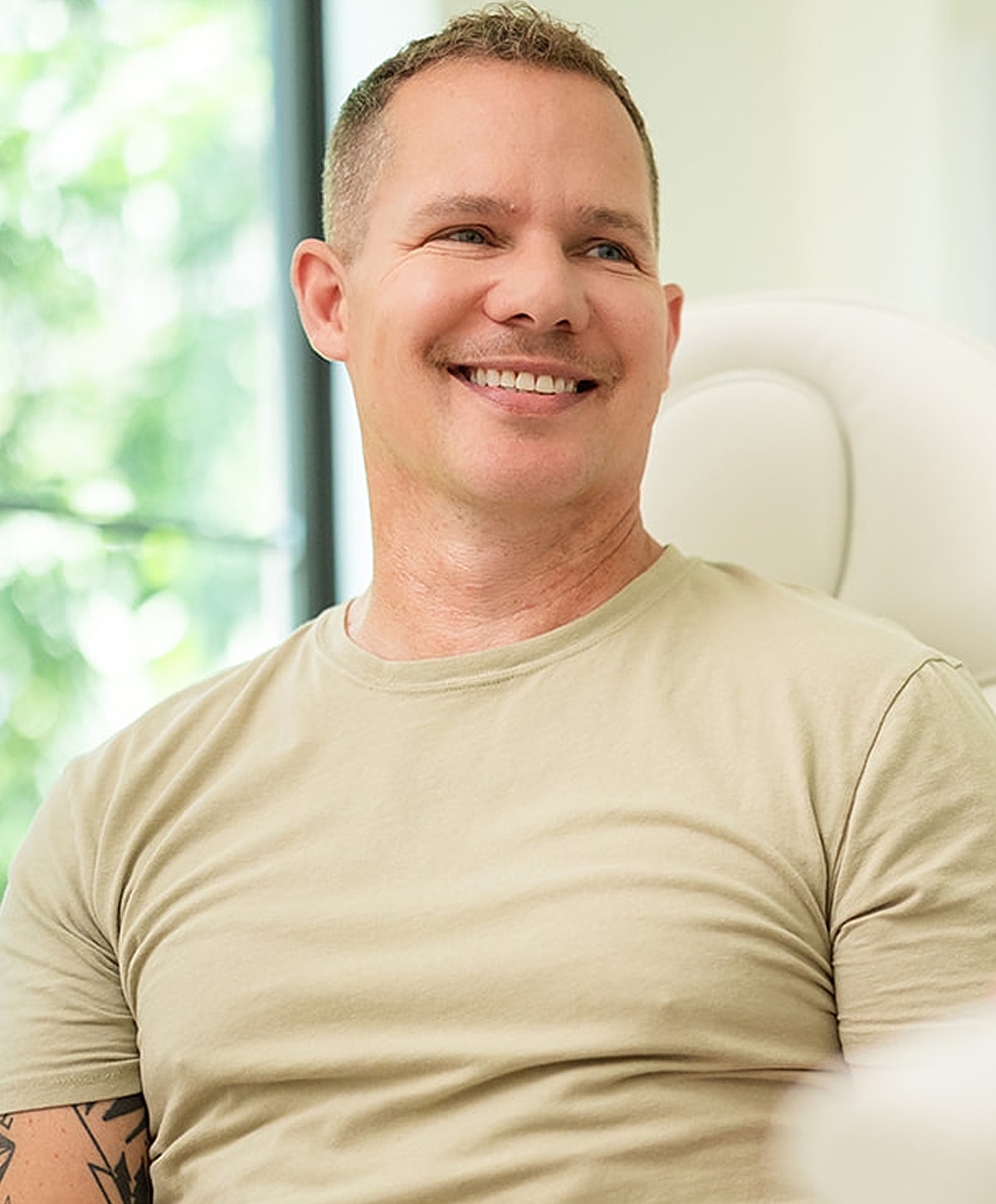 Smiling man in casual attire, relaxed setting.