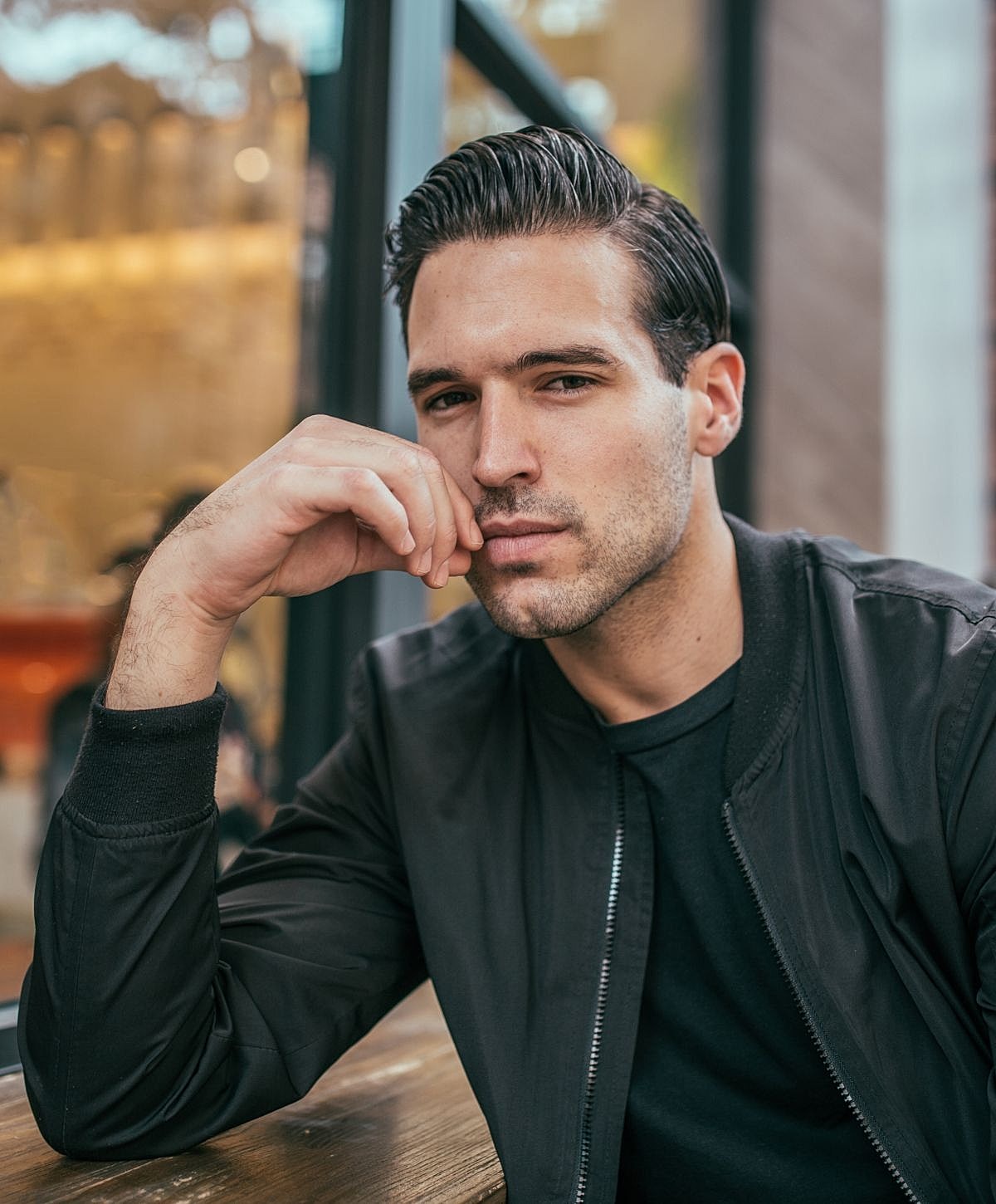 Young man in a black jacket posing thoughtfully.