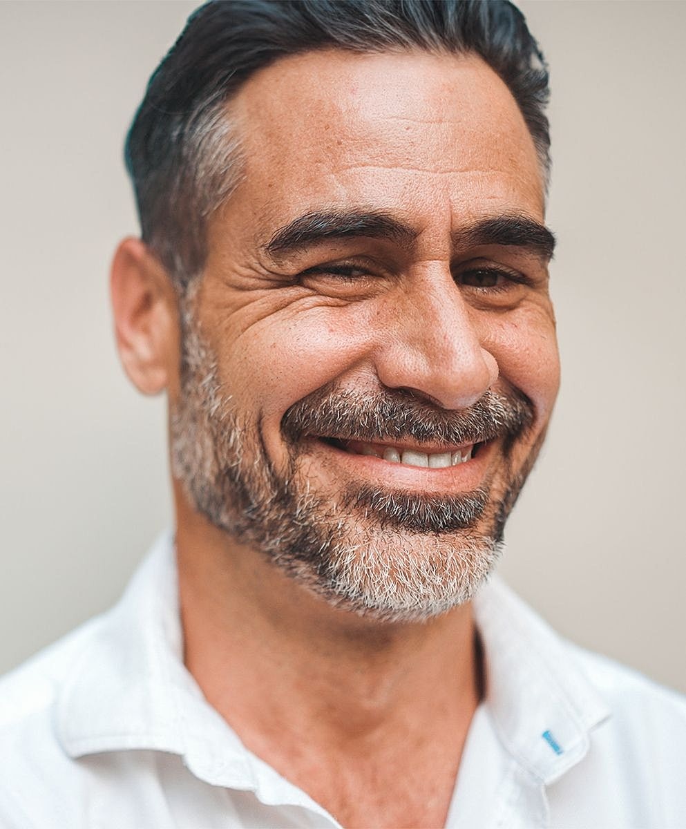 Smiling man with a beard in a white shirt.