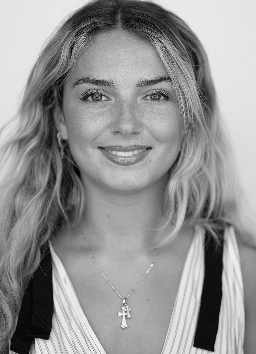 Smiling woman with wavy hair and necklace.