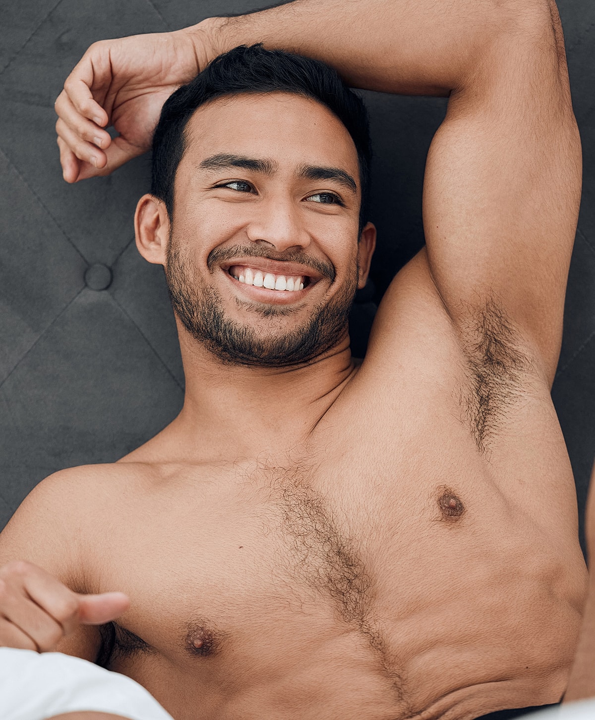 Smiling man relaxing on a dark surface.