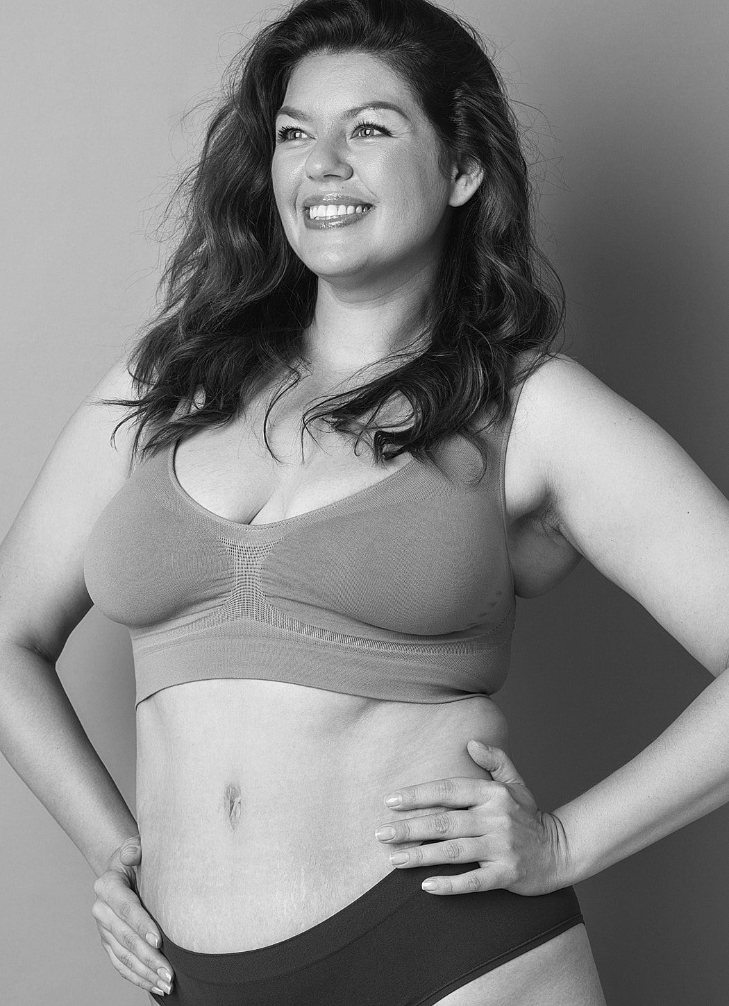 Smiling woman in lingerie, posed confidently.