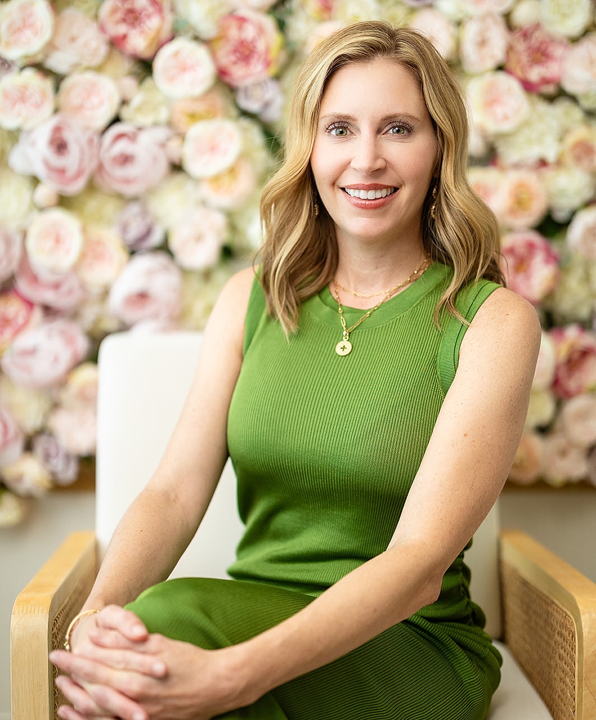 Woman in green dress against floral background.