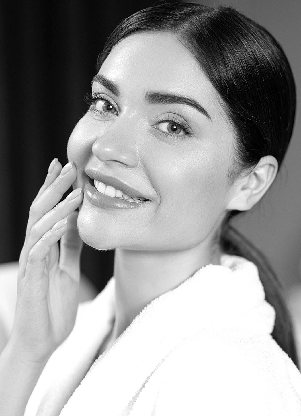 Smiling woman in a spa robe, skincare routine.