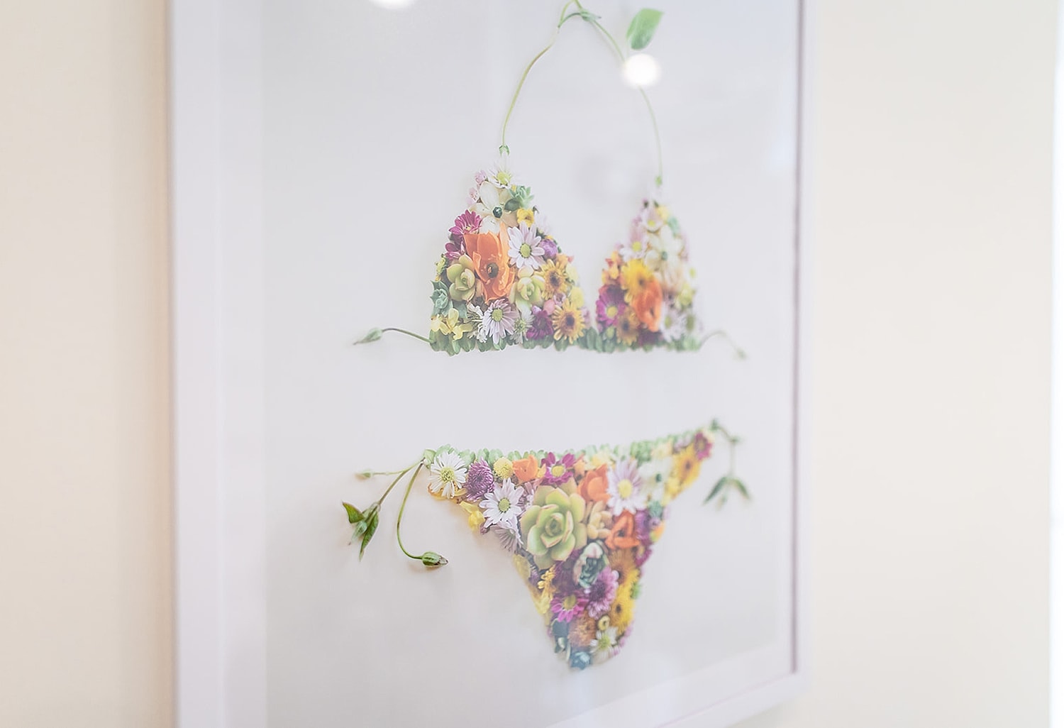 Floral bikini artwork framed on a wall.