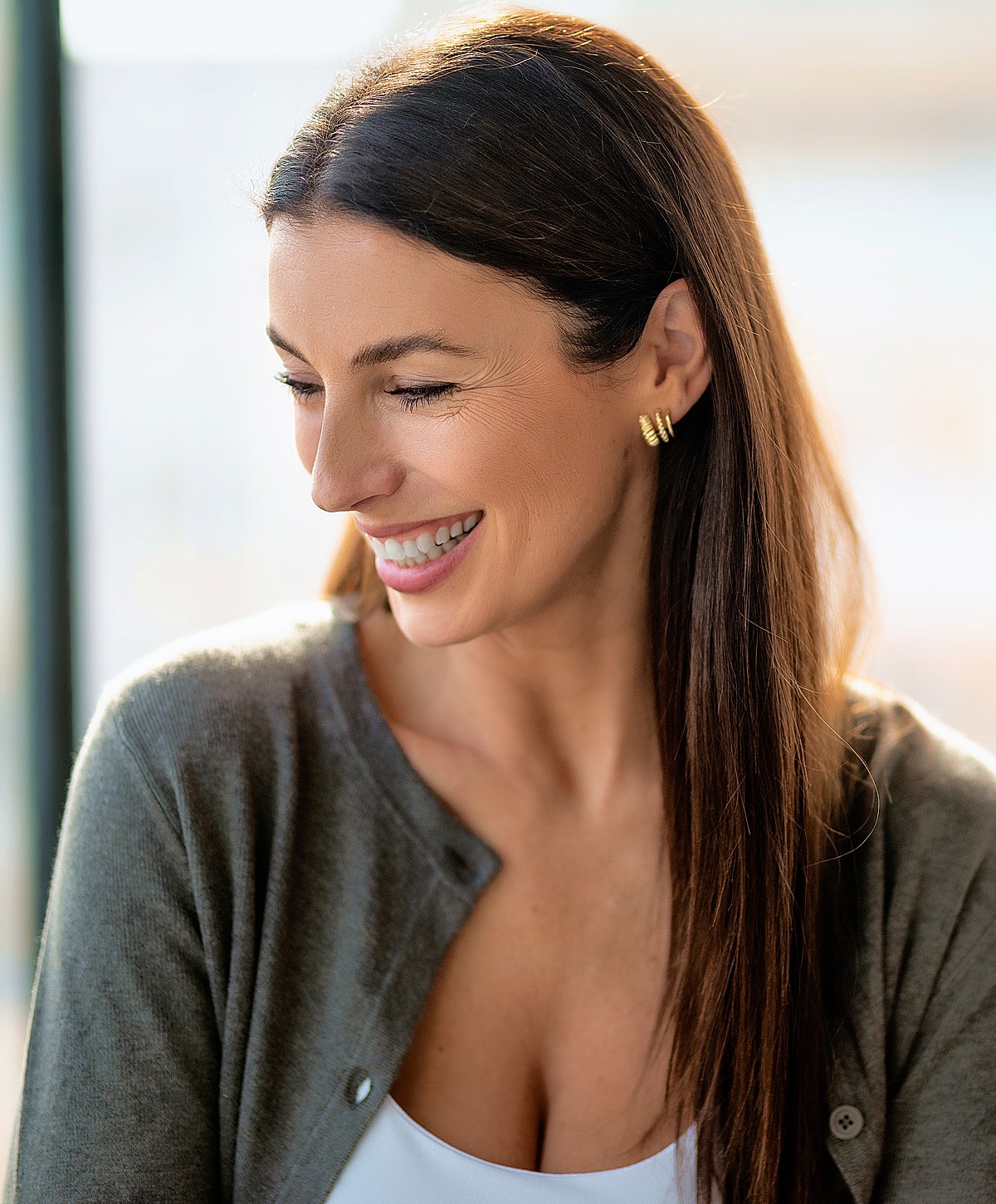 Smiling woman wearing a cardigan and earrings.