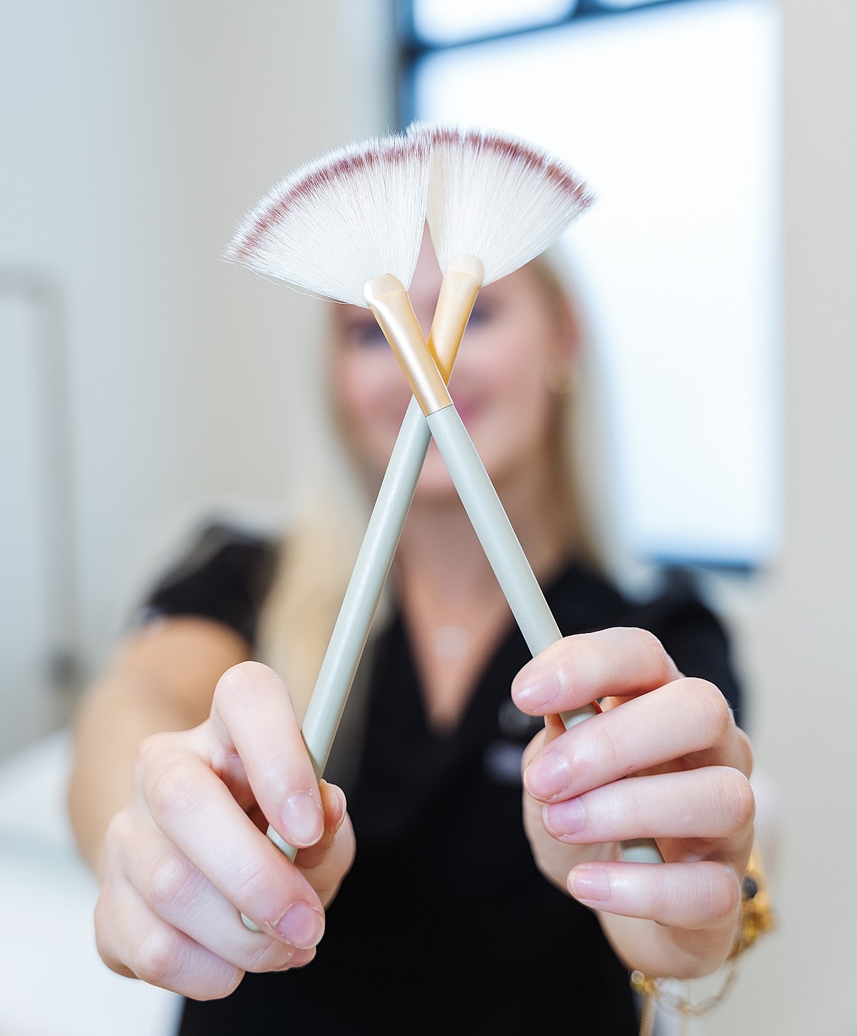 Makeup artist holding fan brushes for application.