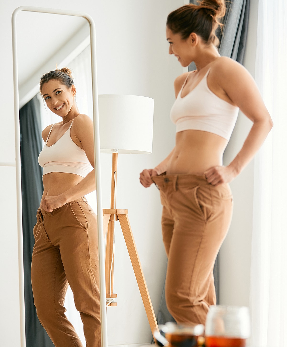 Person trying on oversized pants in mirror.