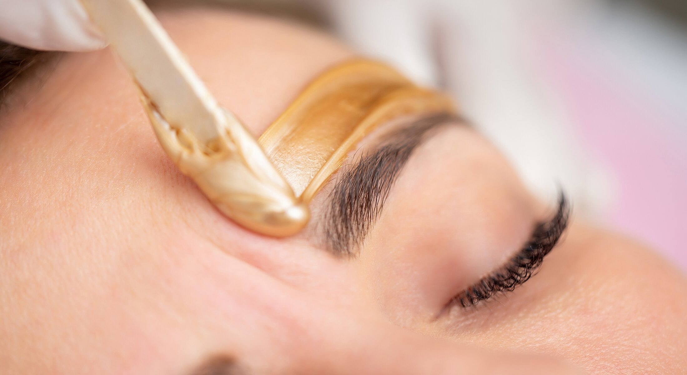 Eyebrow waxing treatment in progress.