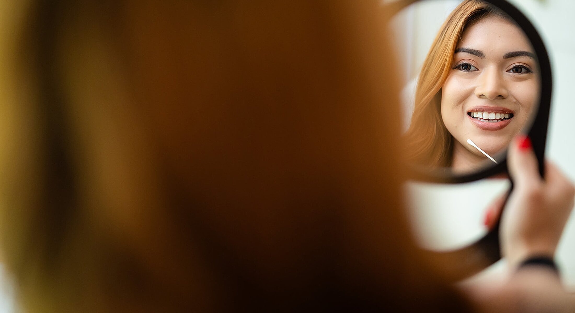 Woman smiling while looking in a mirror.