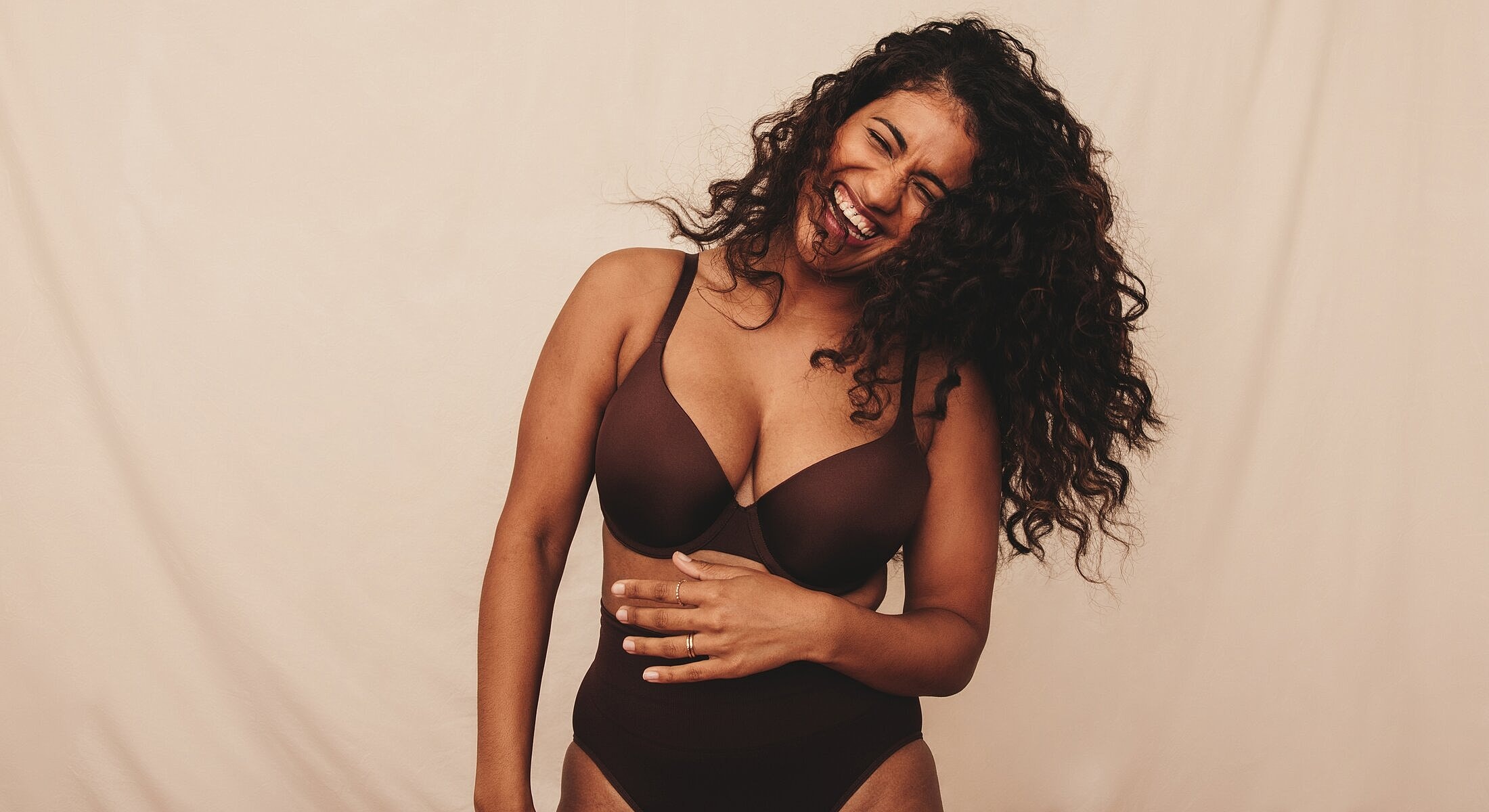 Woman laughing in a brown lingerie set.