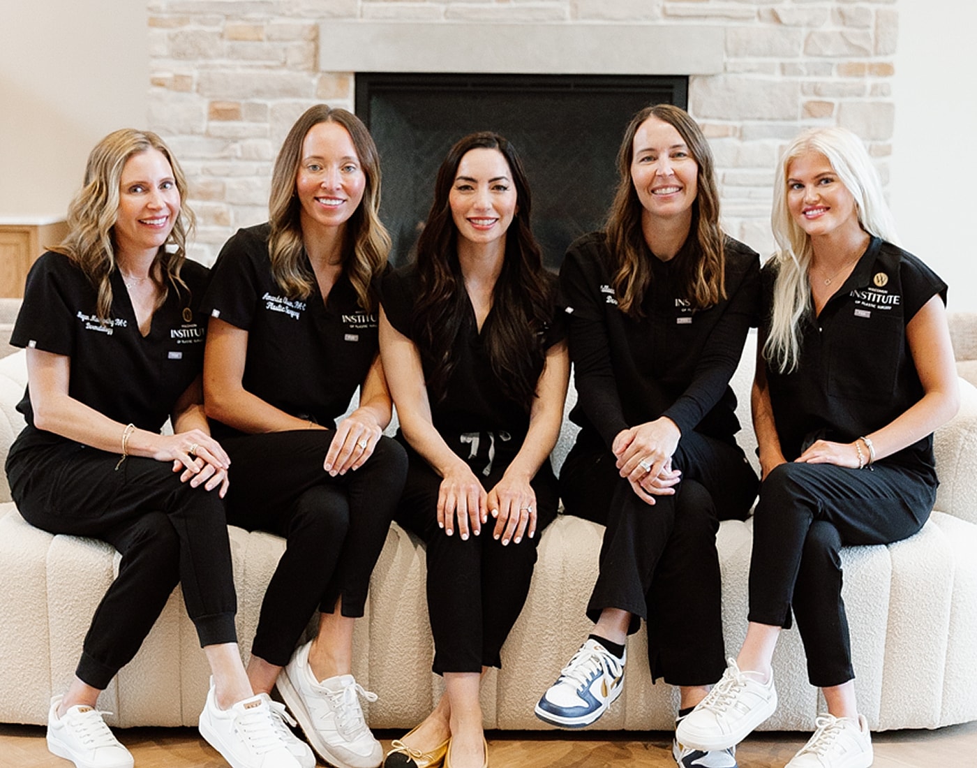Five women in black scrubs, smiling together.