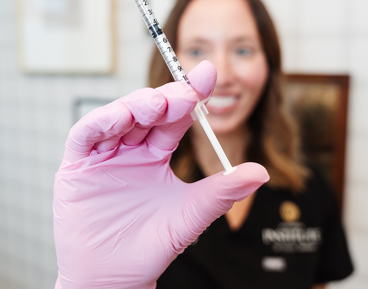 Healthcare professional holding a syringe in gloved hand.