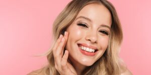 female model young woman looking forward with her hand pressed to her face smiling